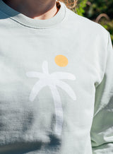 Print detail of a Sutsu Palm Trees Slim Fit Sweatshirt - an organic cotton graphic sweatshirt in green with a palm tree and sun design.
