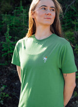 Woman wearing a Sutsu Palm Tree EMB T-Shirt - a green graphic t-shirt with small embroidered palm tree and sun logo.