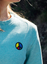 Close up of a light blue Sutsu Simon Says Peace EMB Sweatshirt - organic cotton sweaters with embroidered multi-coloured peace symbol.