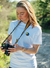 Woman wearing a white Sutsu Simon Says Peace EMB T-Shirt - an organic cotton shirt with embroidered multi-colour peace symbol.