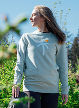 Woman dressed in a Sutsu Palm Trees Slim Fit Sweatshirt - an organic cotton graphic sweatshirt in green with a palm tree and sun design.