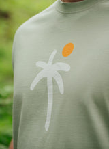 Close up of the design on a Sutsu Palm Tree T-Shirt - a green organic cotton t-shirt with printed palm tree and sun graphic.