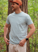 Man wearing a Sutsu Palm Tree EMB T-Shirt - a blue graphic t-shirt with small embroidered palm tree and sun logo.